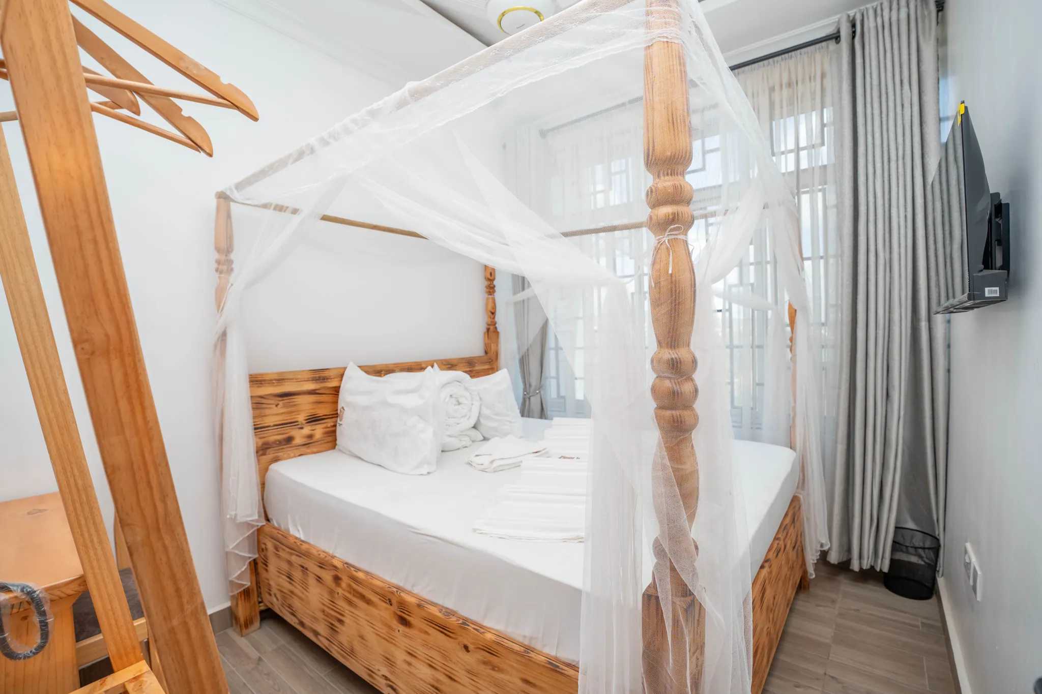 A neatly prepared bed beneath a mosquito net